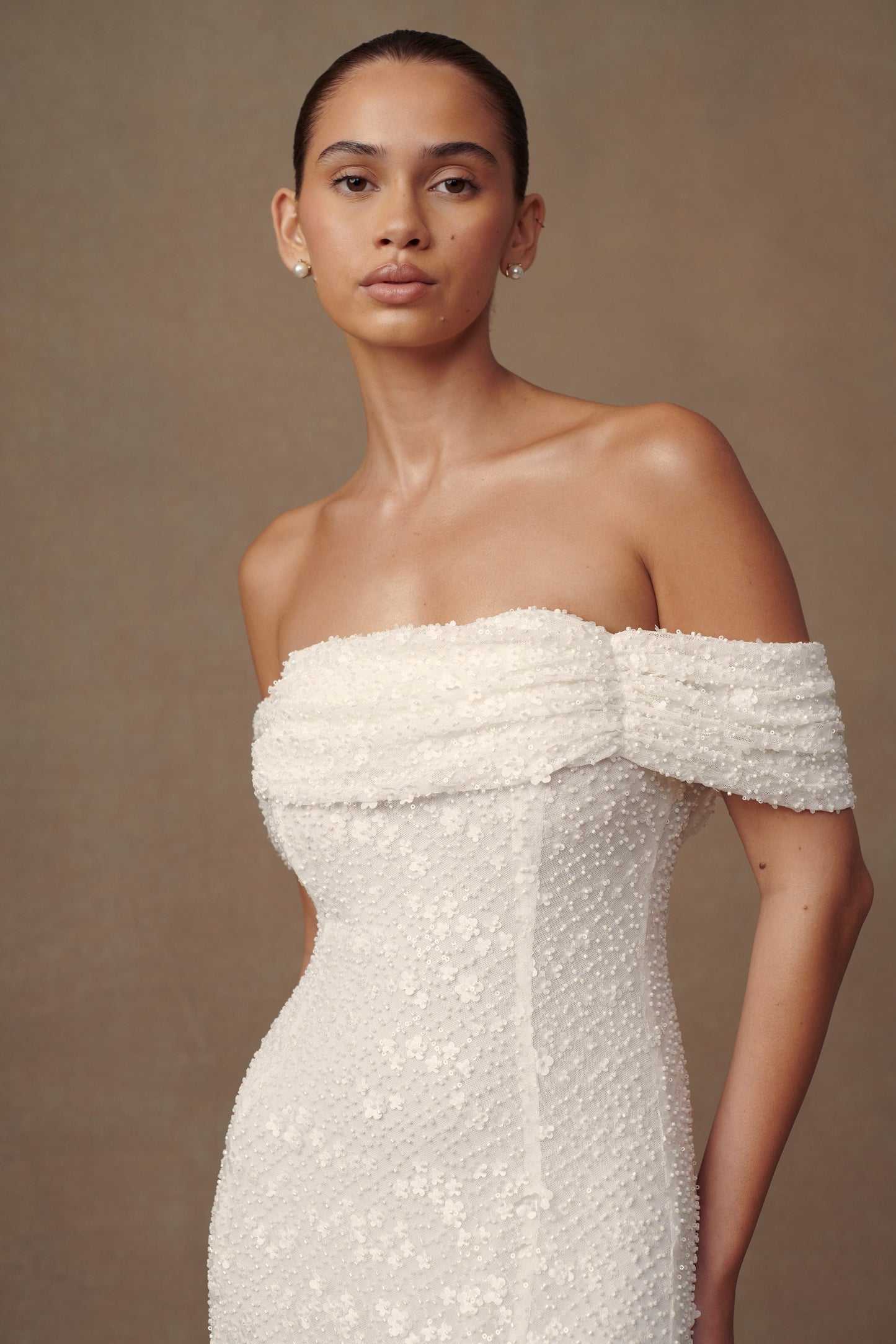 Robe de mariée blanche Priyanka Daisy, perlée et décolletée épaules dénudées.