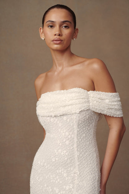 Robe de mariée blanche Priyanka Daisy, perlée et décolletée épaules dénudées.